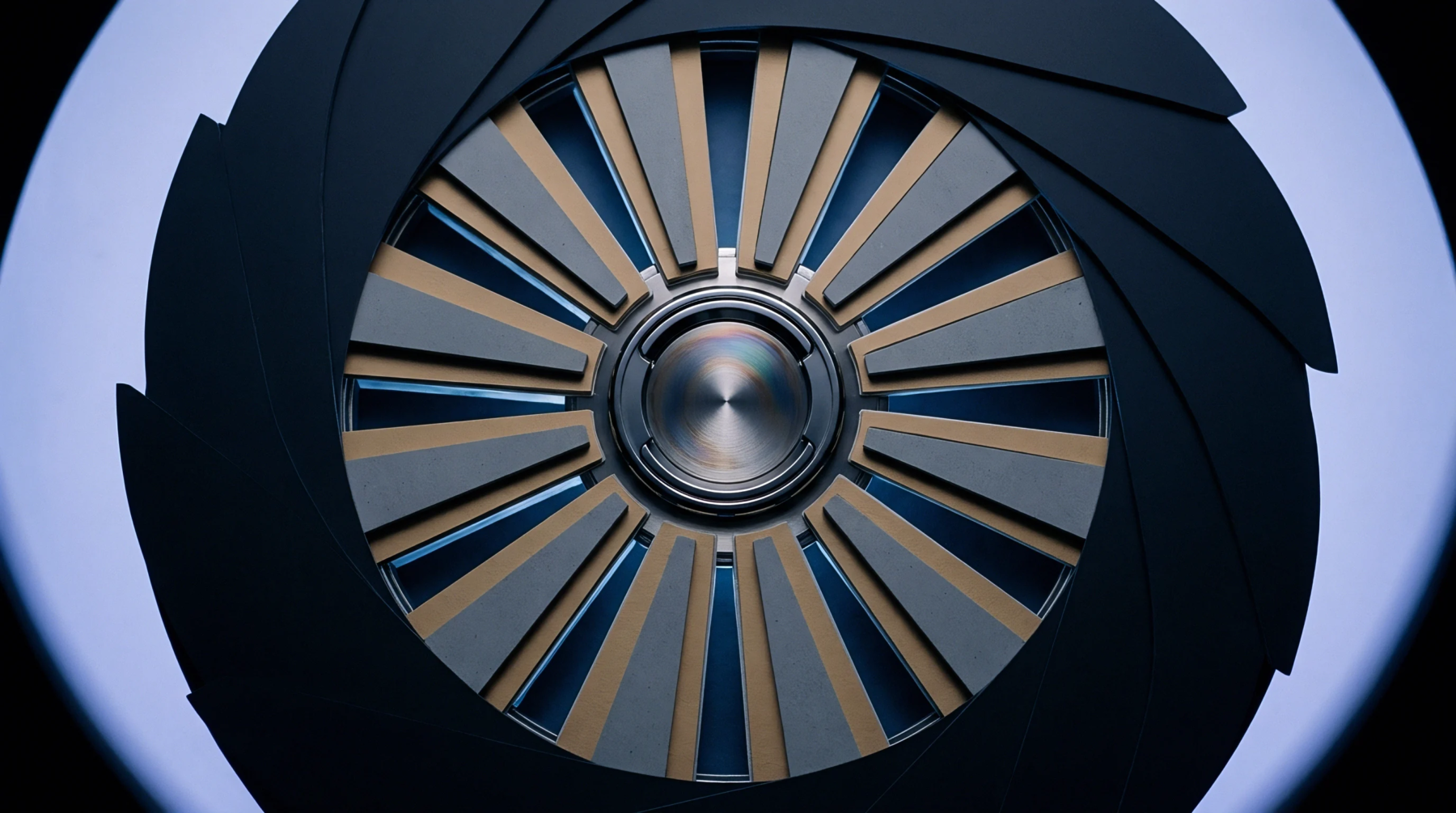 A high precision mechanical iris shutter with overlapping dark blades surrounds a radial metallic central hub while illuminated by a diffuse light source.