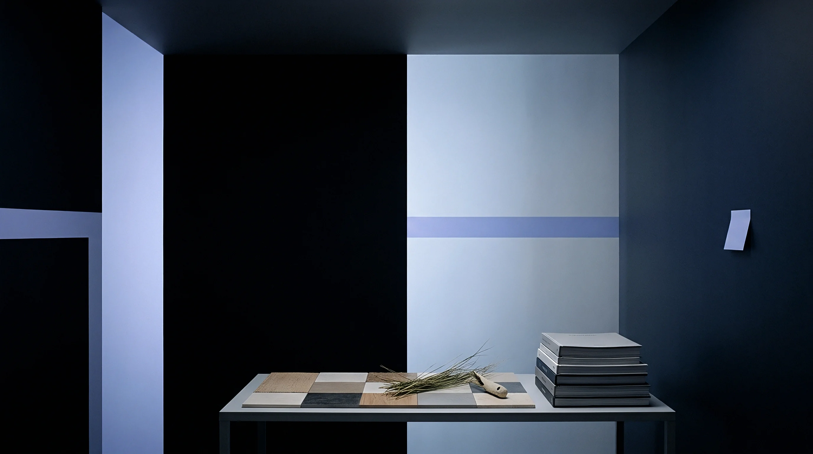A grid of substrate tiles sits on a table beside a stack of bound cardstock and a small piece of dried botanical foliage.